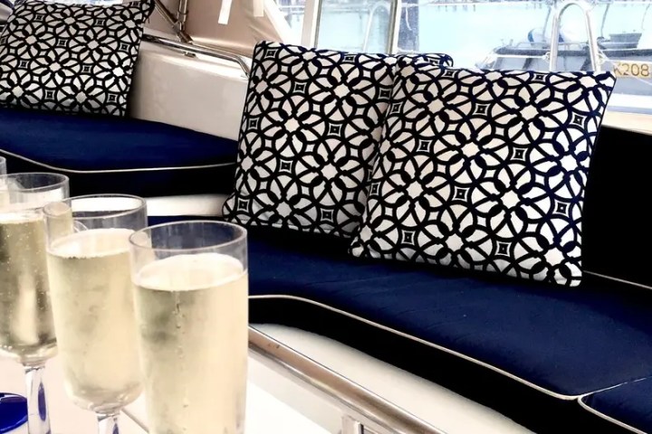 Champagne glasses and patterned cushions on a boat's blue cushioned seating.